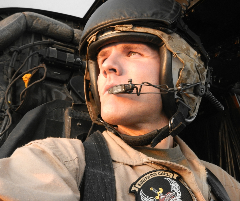 Striking image of am an wearing military gear and helmet with microphone looking away from the camera with sunlight beaming on his face